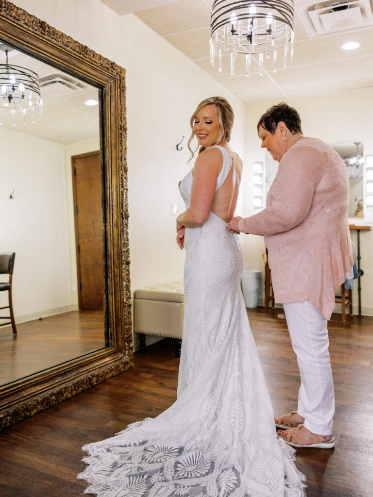 bride into dress with mom